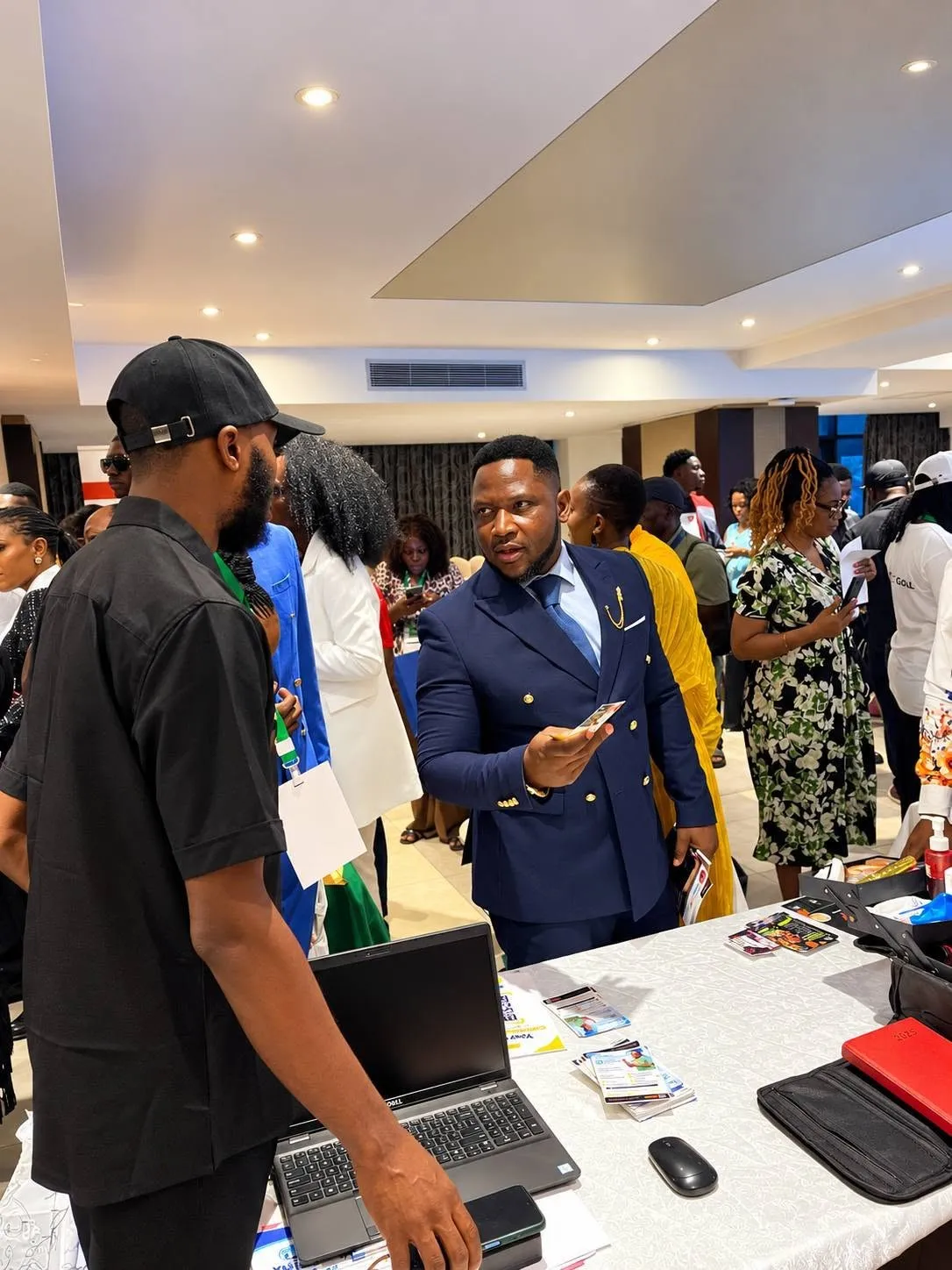 Emmanuel Cobbi talking with a visitor across a Tribe exhibitor table at an event.