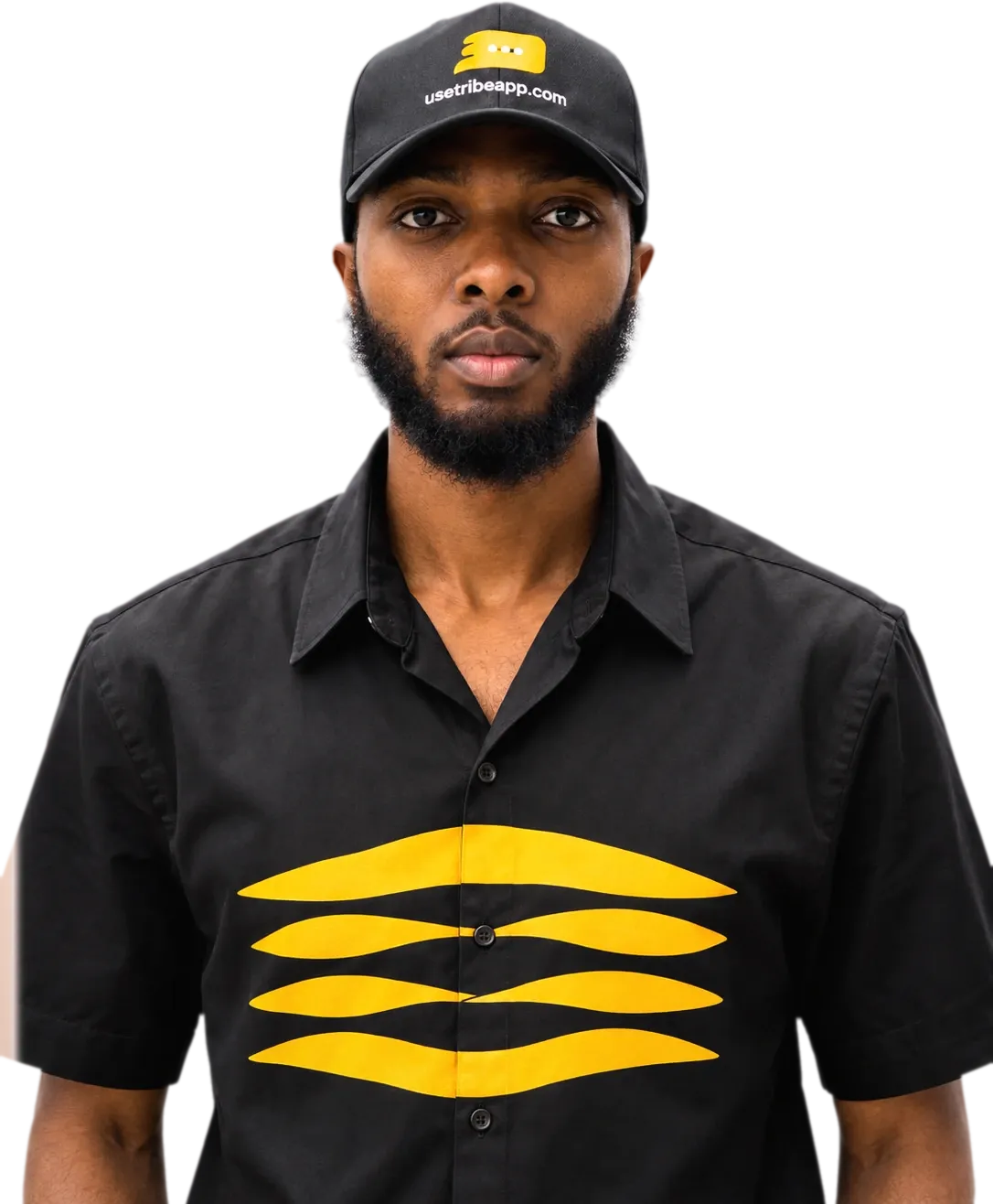 Emmanuel Cobbi photographed from the chest up in a black Tribe cap and a black shirt carrying the yellow Tribe mark.